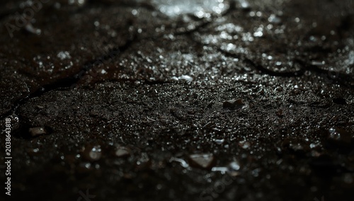 Close shot of wet soil texture with water droplets on dark ground surface and open copy space