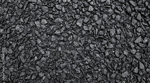 Top view of highdetail black asphalt texture with rough crushed stone and coarse gravel perfect for industrial construction roadwork and dark