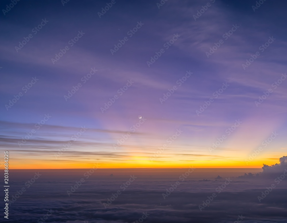 Fototapeta premium Panoramic horizon view of tranquil twilight sky, displaying gradients of deep purple and fiery orange, sun rays illuminating clouds, subtle moon