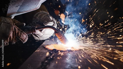 Close-up of a welder's torch igniting a brilliant display of sparks on metalwork