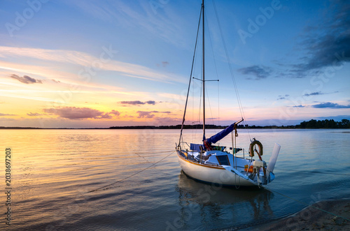 Quadro su tela Sailboat moored to the shore during sunset, Lake Kisajno, Pierkunowo in Masuria, Poland
