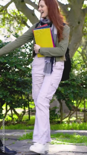 Vertical video: Walking redhead with notebook, spotting bench friend using tablet, sitting chatting