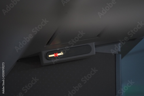 Commercial aircraft cabin illuminated no smoking sign close-up