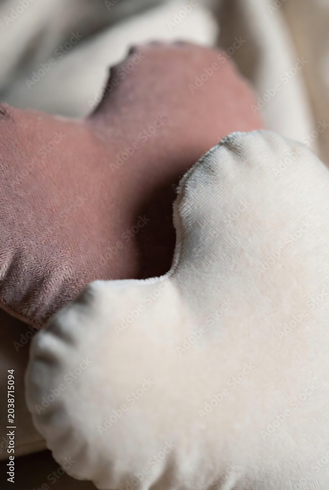 Naklejka premium Soft, plush pillows in shades of dusty rose and cream are visible in a close-up shot.