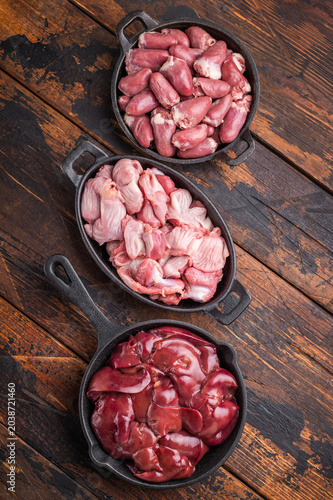 Tableau sur toile Fresh raw poultry offal assortment with duck hearts, liver, and gizzards on dark rustic wood table, organic cooking concept