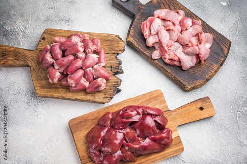 Photography Assorted raw giblets including hearts, liver, and gizzards on vintage wooden boards, organic poultry cooking concept
