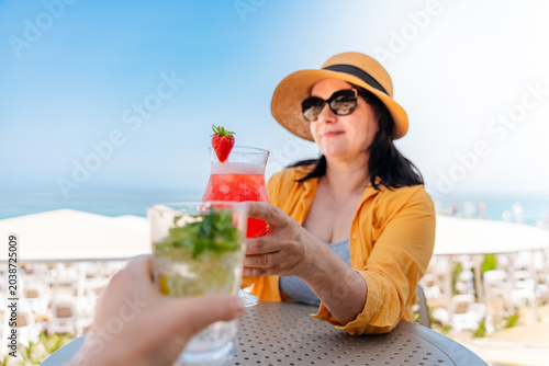 Photography Woman enjoying a refreshing summer cocktail at a seaside resort terrace