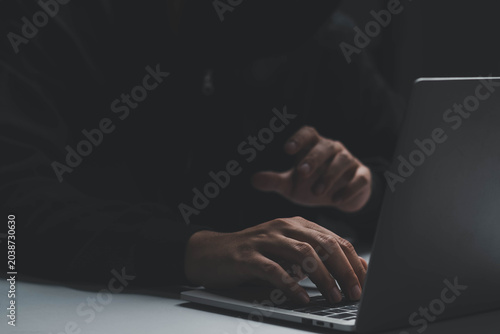 Anonymous hacker using laptop in dark environment, cybersecurity threat concept, data breach and hacking activity, online privacy risk, cybercrime attack, digital security and information theft
