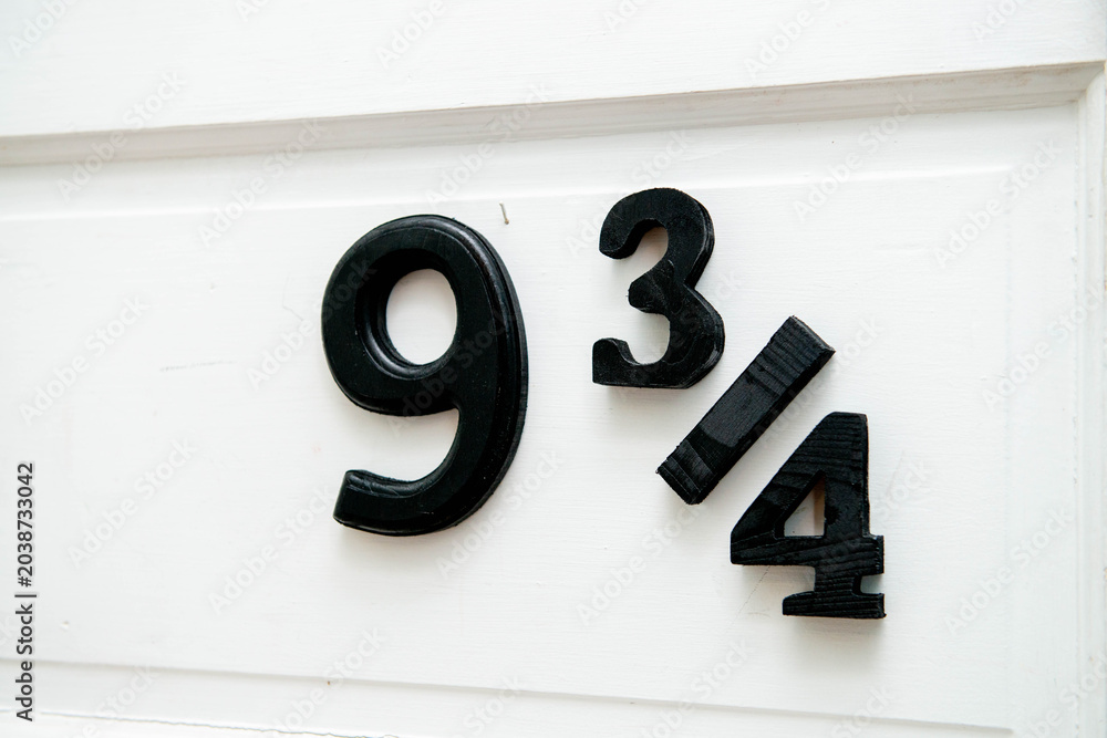 Naklejka premium Close-up of a white front door to a bookstore or house with the numbers 9 3/4 posted in large black numerals. The building's street address calls to mind the hidden train station entrance Harry Potter