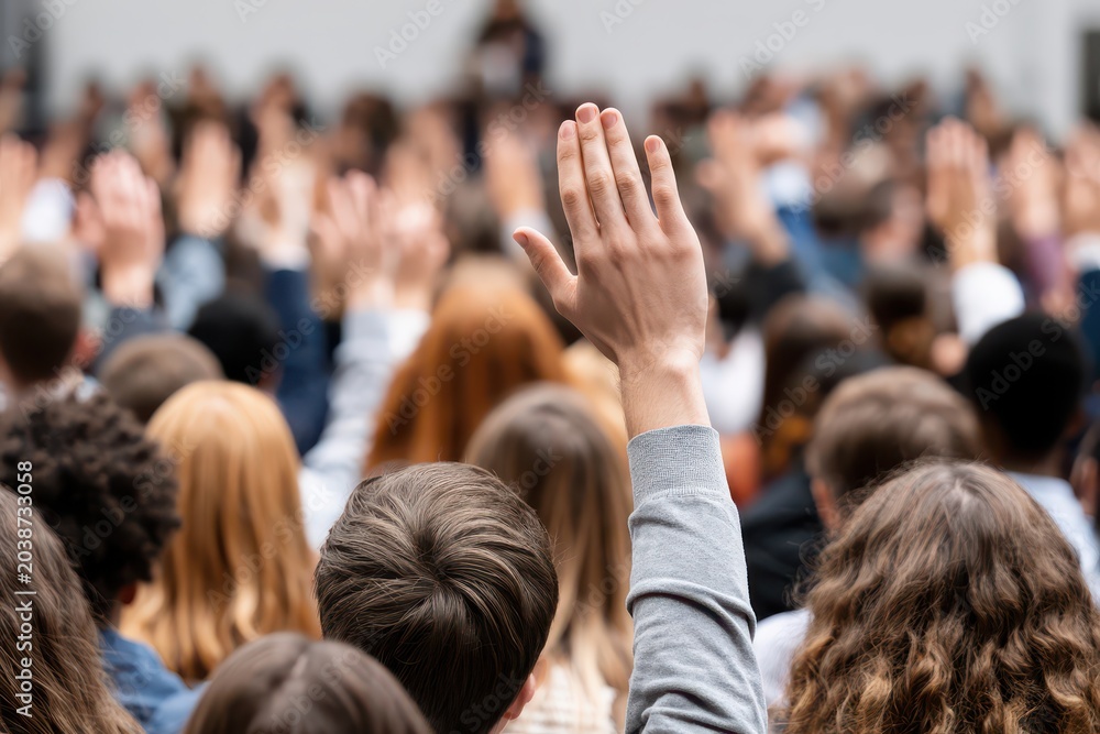 Obraz premium A diverse group of people raising their hands in a large crowd, participating in an event.