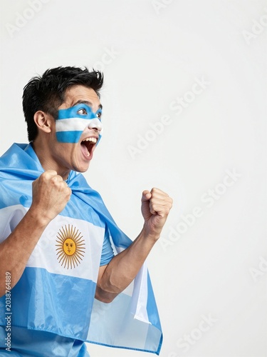 Excited sports fan cheering with Argentine flag and face paint