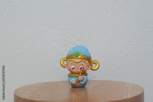 Cute oriental character mini figurine on a wooden table against a white wall background