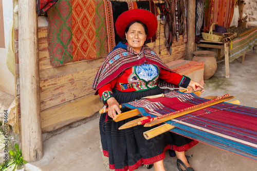 Canvas Print Peruvian woman weaving colorful textile on traditional wooden loom in artisan wo