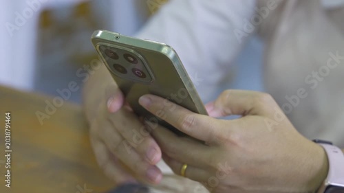 Close up of woman hands holding and using a modern smartphone at a table.