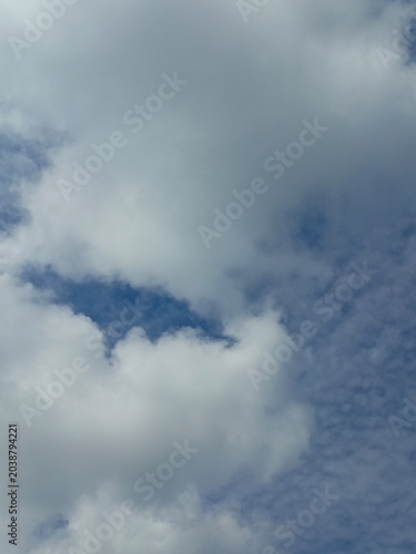 Foto Fluffy white cumulus and textured altocumulus clouds in a blue sky