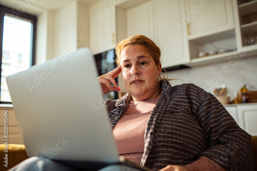 Billede på lærred Concerned woman working on laptop at home
