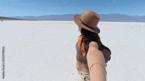 Young woman vlogging her exciting adventure while spinning happily in a vast, white salt desert