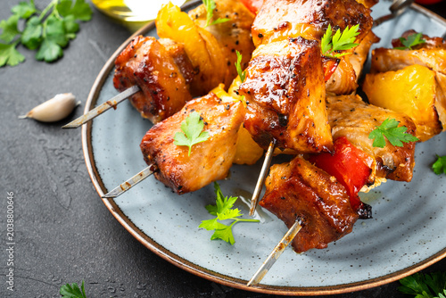 Photos Grilled shish kebab, Grilled meat skewers with vegetables and herbs on black background