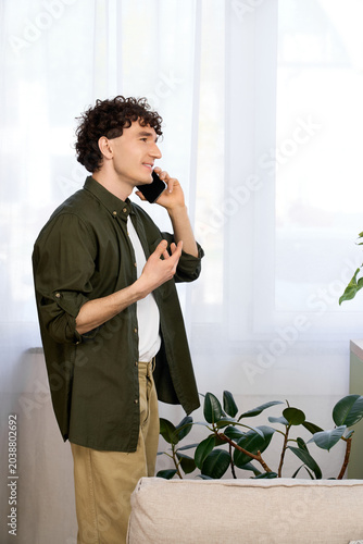 фотографія Joyful moments in a modern apartment with a casual young man on a phone call