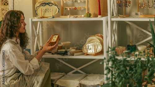 Woman examining handmade wooden candle in a cozy artisan workshop setting