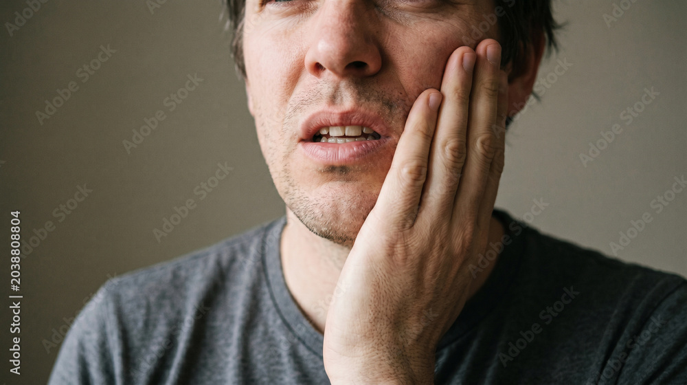 Fototapeta premium Man Pressing His Cheek While Dealing with Severe Toothache