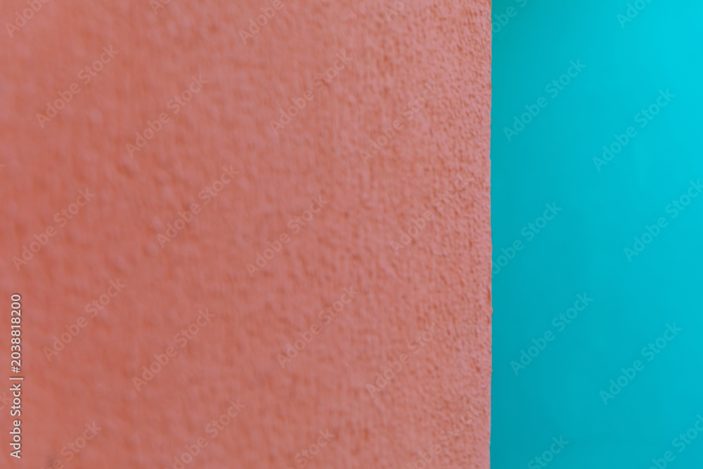 Fototapeta premium Abstract view of a textured orange wall meeting a smooth cyan background. Minimalist design, architectural detail, color contrast.
