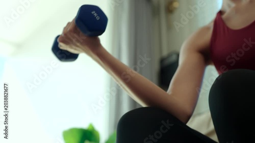 Close-up Young woman doing strength training with dumbbells and kettlebells at home. Fitness for longevity, healthy aging, muscle strength, wellness and active lifestyle concept.
