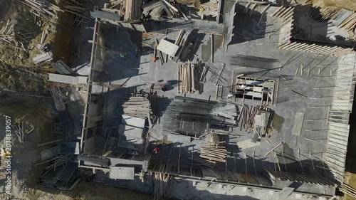 Aerial Video of Rooftop Slab Pouring Process With Concrete Mixers, Reinforcement Bars, and Workers Spreading Materials in Sunlight