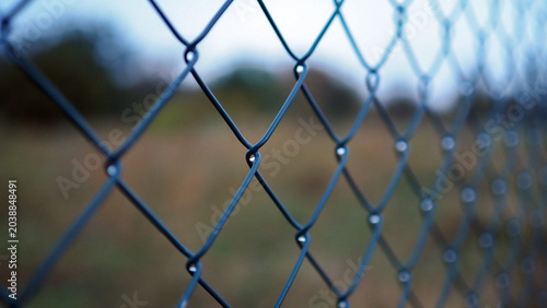 Close up of a metallic chain link fence. Background texture of a silver wire mesh fencing structure outdoors. Conceptual industrial pattern of steel security barrier and boundary grid.