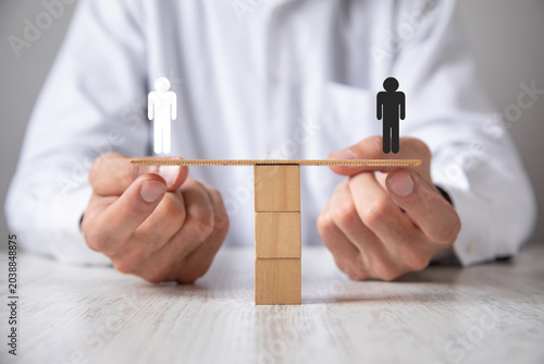 Foto Caucasian businessman showing human symbols on wooden scales.