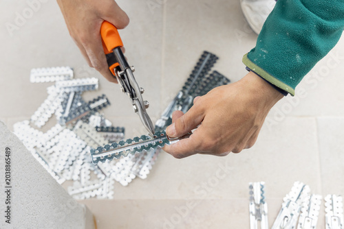 Foto Drywall worker cutting metal profile with tin snips during suspended ceiling ins