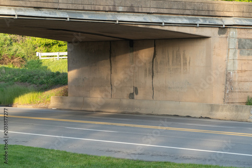 Foto Underneath a Concrete Highway Overpass: An Empty Two-Lane Asphalt Road with Gree