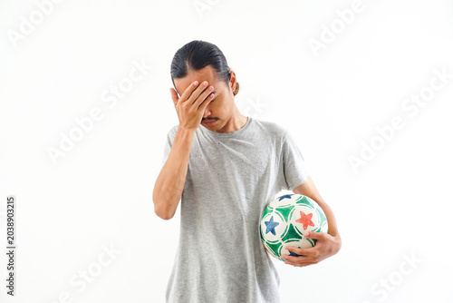 Young man holding colorful soccer ball indoors with surprised expression