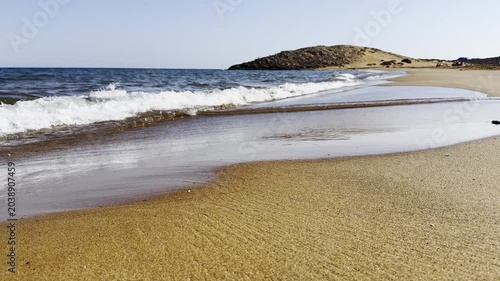 The sea water sparkles in the sun, grinding the sand. High quality 4k footage