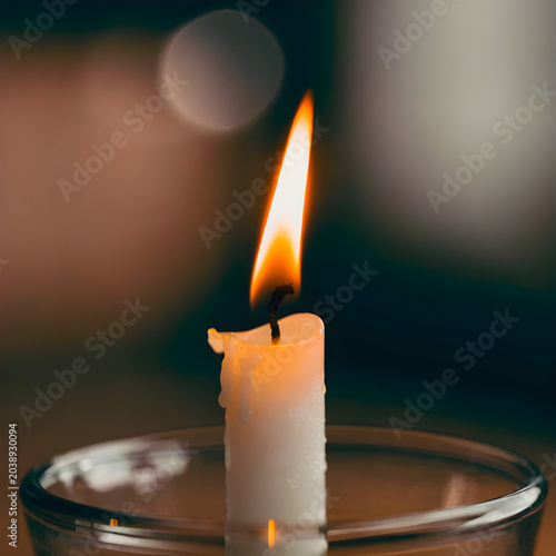 Single lit white candle flame burning in a dark peaceful room atmosphere