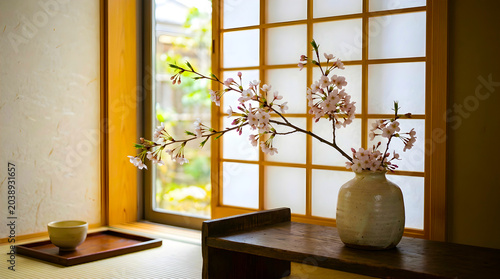 Cherry blossom branches in ceramic vase inside traditional japanese tea room
