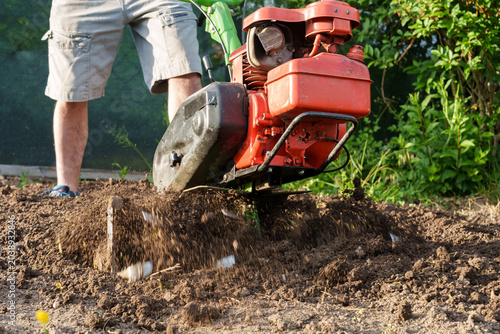 Принти на полотні Man using motor cultivator to loosen soil in garden close up