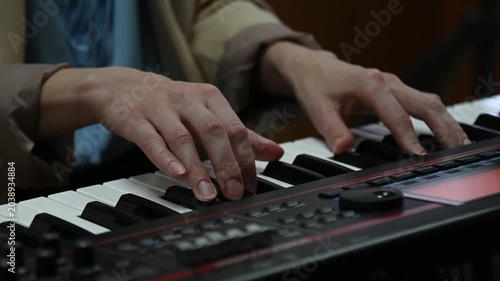 female pianist hands on black and white synthesizer keyboard, close-up view, young woman playing piano, professional musician