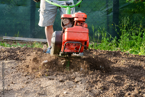 Принти на полотні Man using motor cultivator to loosen soil in garden close up
