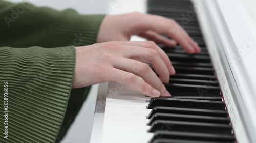 female pianist hands on black and white synthesizer keyboard, close-up view, young woman playing piano, professional musician