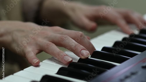 female pianist hands on black and white synthesizer keyboard, close-up view, young woman playing piano, professional musician