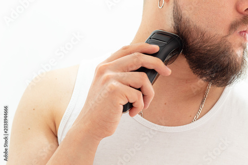 Fotografie Close-up of a man trimming his beard with a cordless shaver on a clean white bac