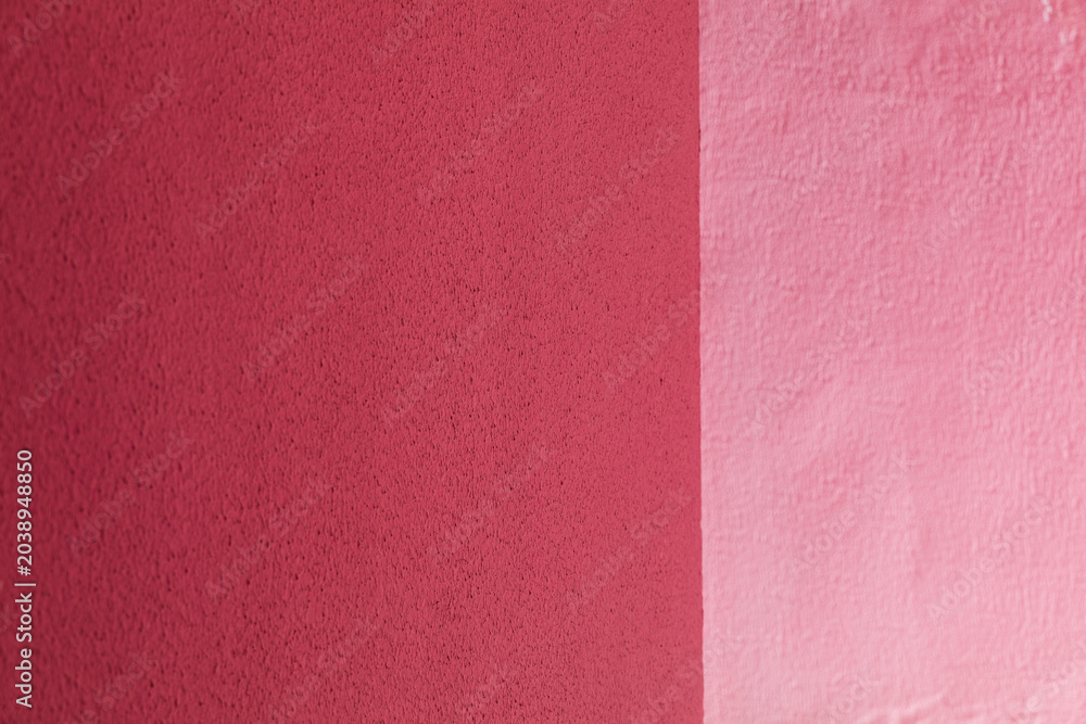 Fototapeta premium A textured wall surface painted in contrasting shades of dark and light pink divided by a vertical line, abstract background, minimalist design, vibrant color contrast.