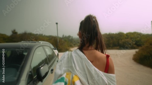 Female in white moves toward beach access through parking area