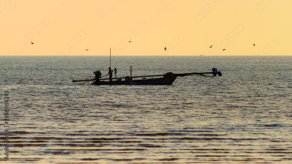 Fototapeta premium Traditional Thai fisherman working on a wooden longtail boat at golden hour.