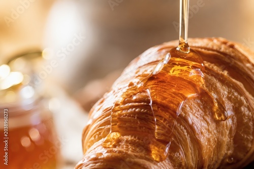 Golden honey dripping over fresh baked croissant macro