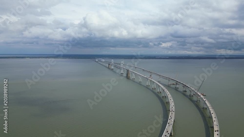 Drone perspective of vehicles traveling across the Chesapeake Bay Bridge in Maryland, spanning the expansive waters of the Chesapeake Bay and showcasing a dynamic transportation landmark.