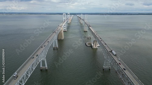 Aerial drone view of the Chesapeake Bay Bridge in Maryland, showing vehicles moving in both directions across the iconic bridge as it stretches over the calm waters of the Chesapeake Bay