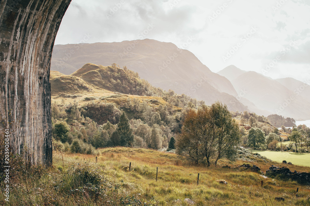 Naklejka premium The historic Glenfinnan Viaduct surrounded by lush green hills, Scottish Highlands