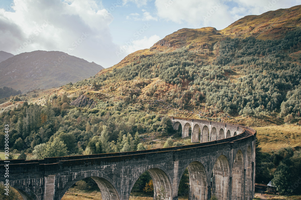 Naklejka premium The historic Glenfinnan Viaduct surrounded by lush green hills, Scottish Highlands